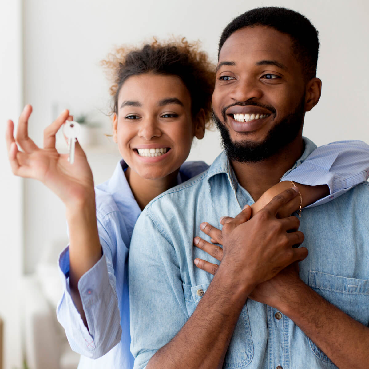 Un couple heureux s'enlace en tenant la clé de leur nouvel maison où il vient d'emménager.